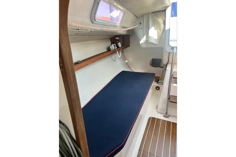  Yacht Photos Pics 2005 J Boats J/100 cabin interior with blue cushioned berth and wooden flooring.