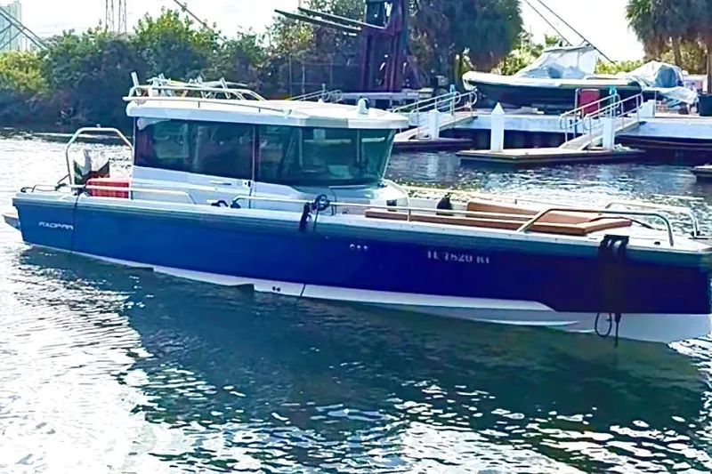  Yacht Photos Pics 2019 Axopar 28 Cabin boat docked in a marina, surrounded by water and greenery.