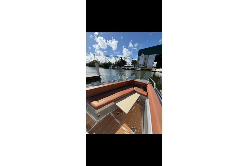  Yacht Photos Pics 2019 Axopar 28 Cabin boat interior with brown seating, docked by a marina.