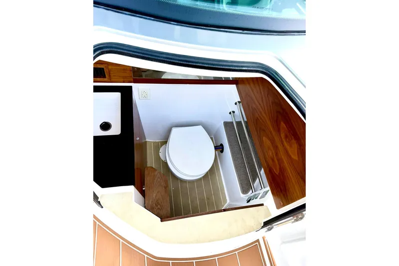 Yacht Photos Pics 2019 Axopar 28 Cabin boat interior with compact bathroom and wooden accents.