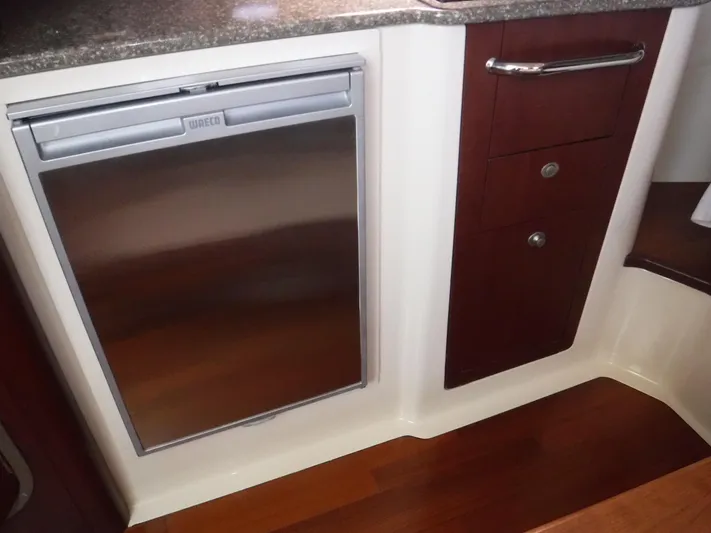  Yacht Photos Pics Interior of 2008 Boston Whaler 345 Conquest, featuring a compact kitchen area with fridge and cabinets.