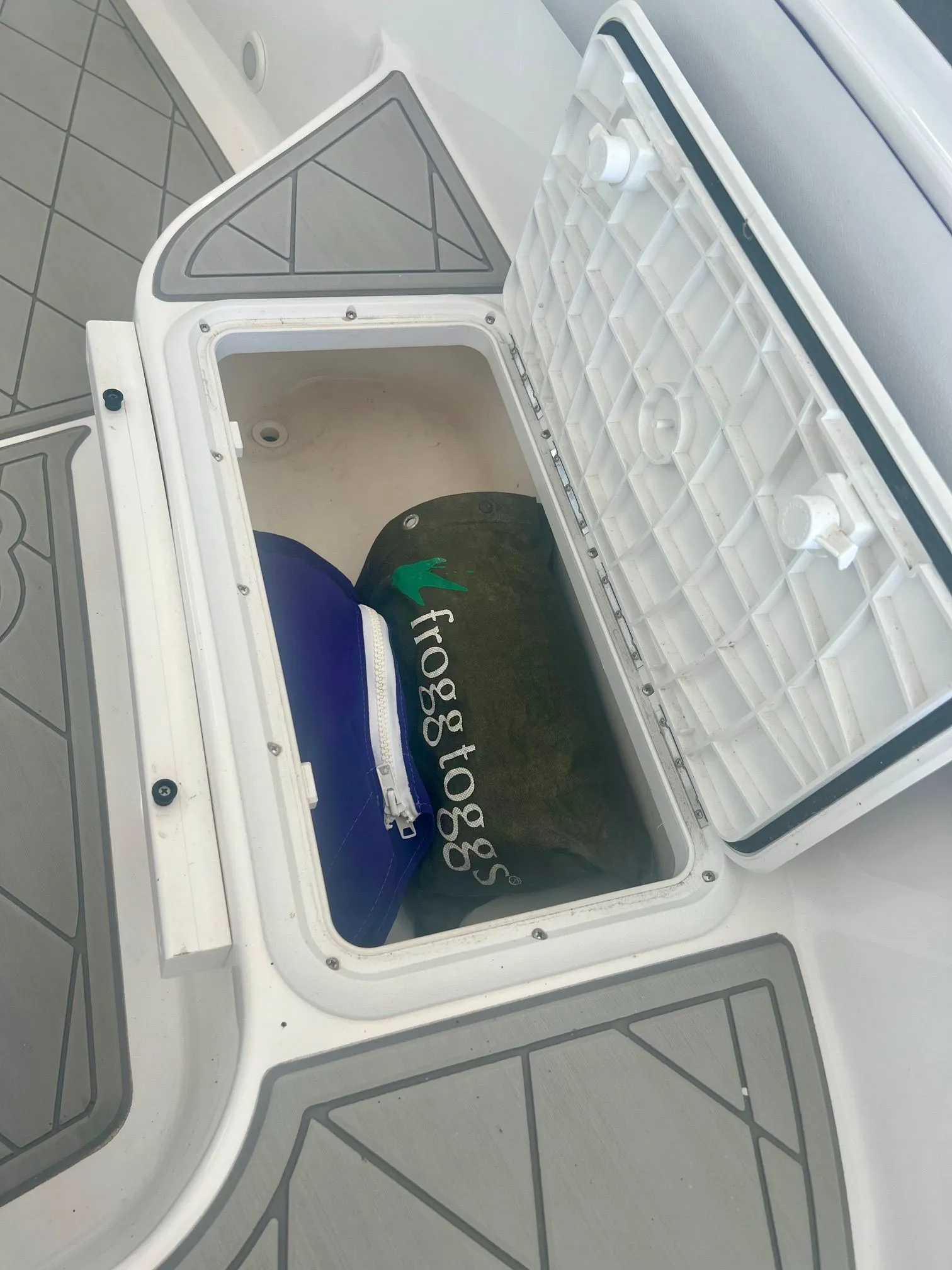 Open storage compartment with Frogg Toggs bag on a boat.