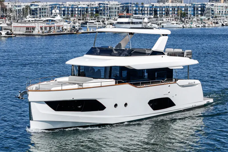  Yacht Photos Pics 2024 Absolute 58 Navetta yacht cruising in a marina with modern architecture in the background.