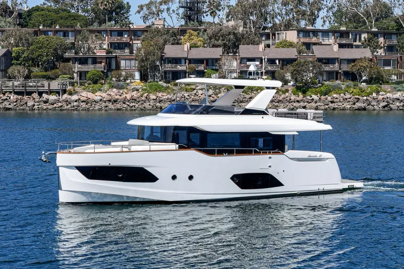  Yacht Photos Pics 2024 Absolute 58 Navetta yacht cruising on a serene waterway near residential buildings.