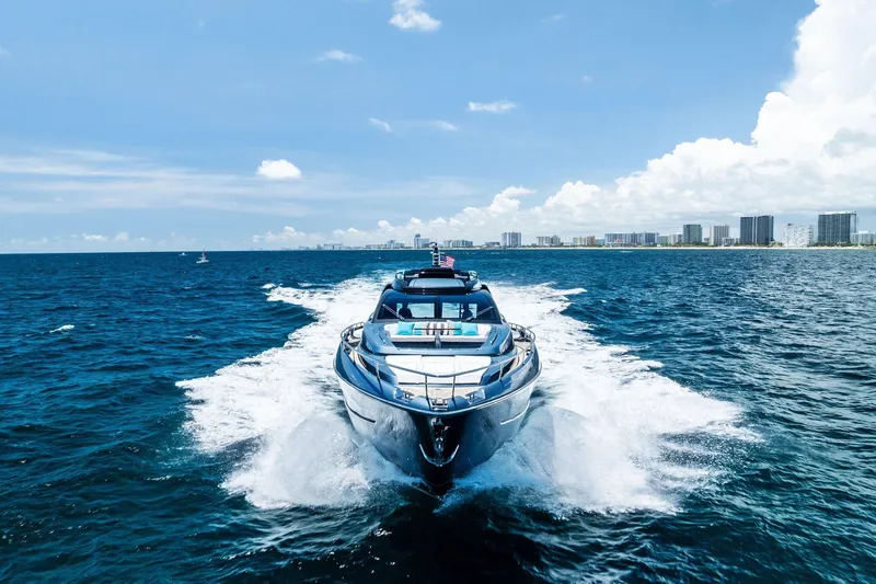 Momentum Yacht Photos Pics 2024 Riva 76 PERSEO Super yacht cruising on open sea with city skyline backdrop.