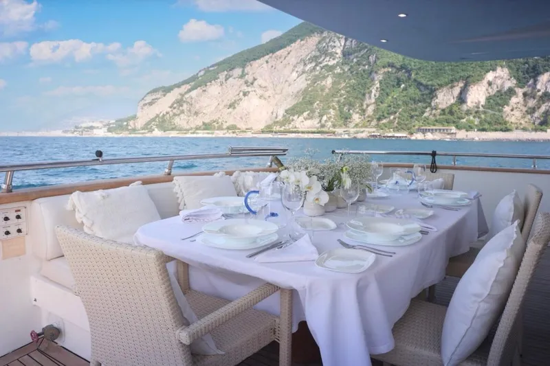 Lady A Yacht Photos Pics Luxurious dining setup on Maiora 29 DP yacht, 2000, with scenic ocean and mountain views.