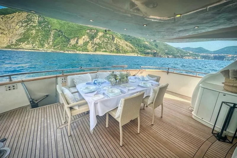 Lady A Yacht Photos Pics Luxury dining setup on Maiora 29 DP yacht, 2000, with scenic ocean and mountain views.