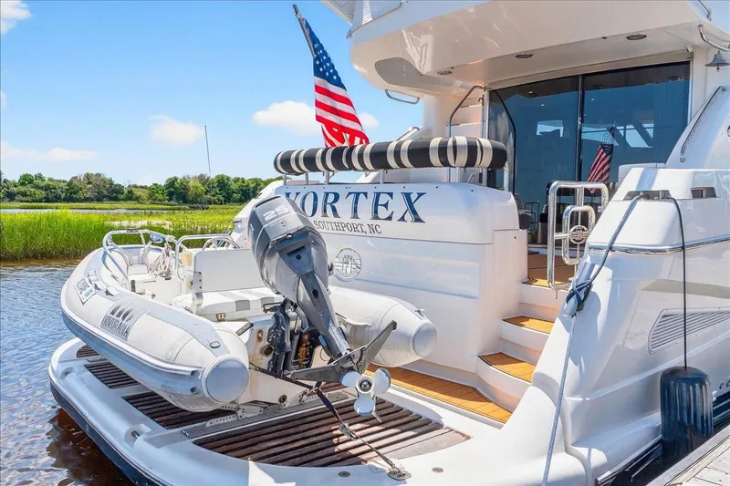 Vortex Yacht Photos Pics 2004 Neptunus 56 Flybridge yacht with tender, docked near lush greenery.