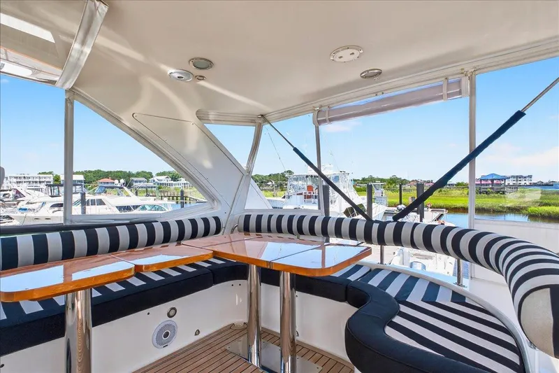 Vortex Yacht Photos Pics Luxurious 2004 Neptunus 56 Flybridge yacht interior with striped seating and wooden table.