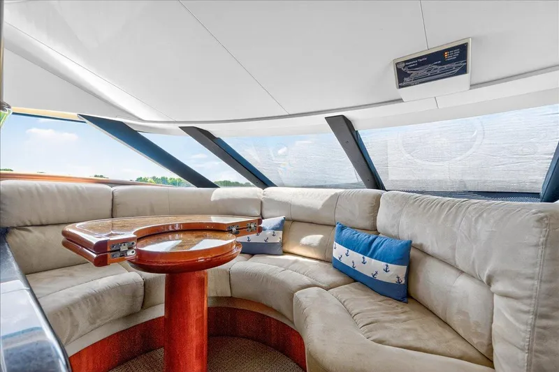 Vortex Yacht Photos Pics Luxurious interior of 2004 Neptunus 56 Flybridge yacht with plush seating and wooden table.