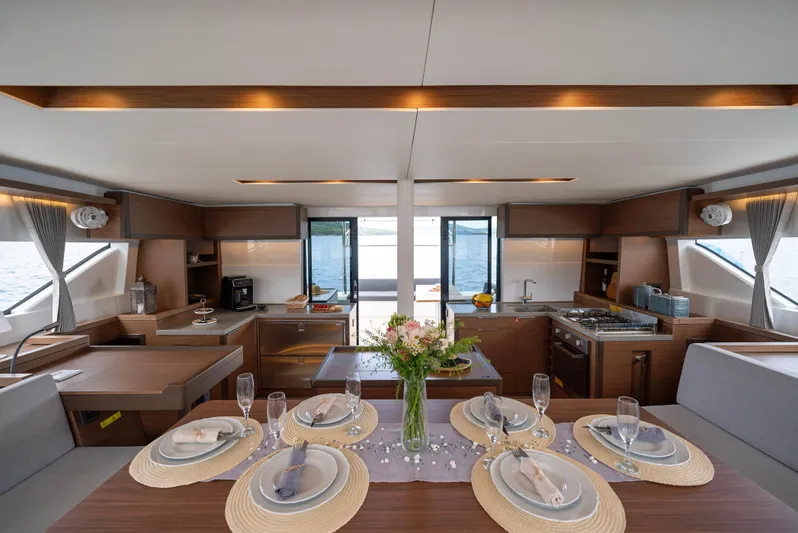 Spellbound Yacht Photos Pics Luxurious interior of 2023 Lagoon 50 yacht with elegant dining setup and modern kitchen.