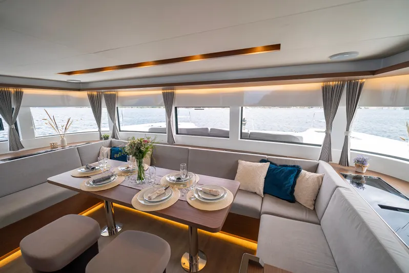 Spellbound Yacht Photos Pics Luxurious interior of 2023 Lagoon 50 yacht with elegant dining setup and panoramic windows.