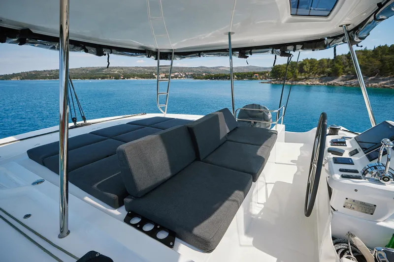 Spellbound Yacht Photos Pics 2023 Lagoon 50 yacht deck with cushioned seating, overlooking serene blue waters.