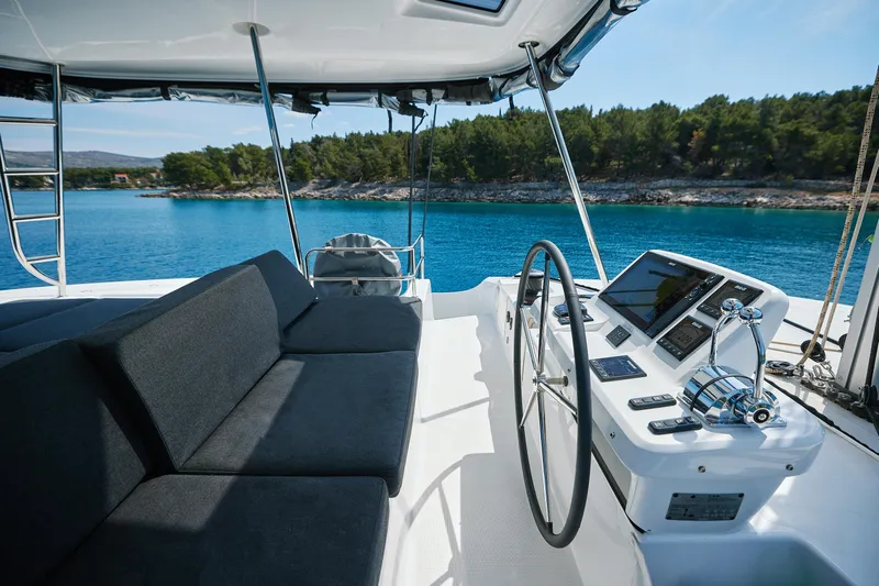 Spellbound Yacht Photos Pics Luxurious 2023 Lagoon 50 yacht interior with modern helm, overlooking serene blue waters and lush coastline.