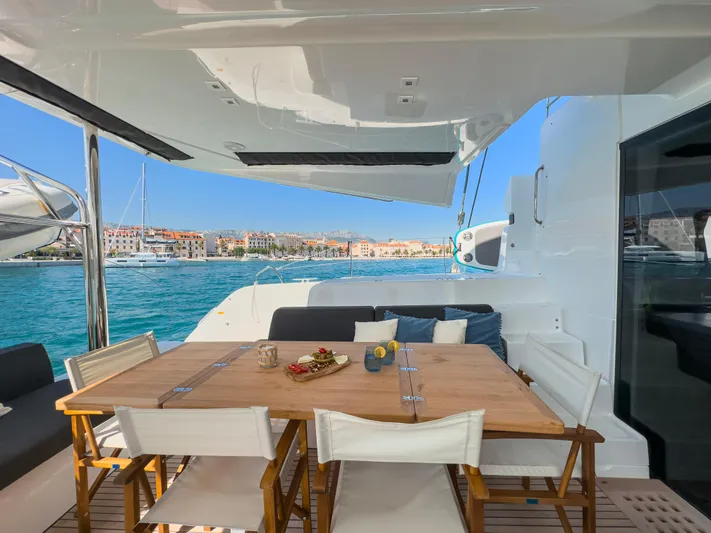 Spellbound Yacht Photos Pics Luxurious Lagoon 50 catamaran deck with dining area, overlooking serene blue waters, 2023 model.