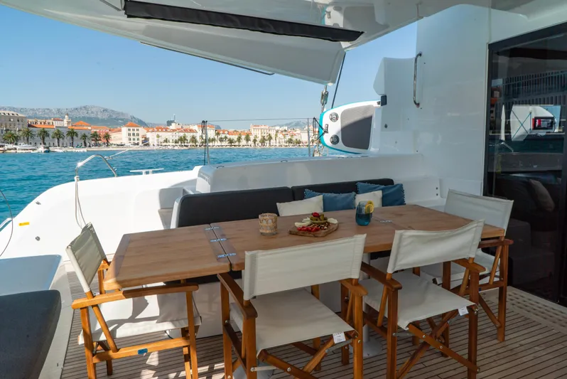 Spellbound Yacht Photos Pics Outdoor dining area on 2023 Lagoon 50 yacht with ocean view and wooden table.