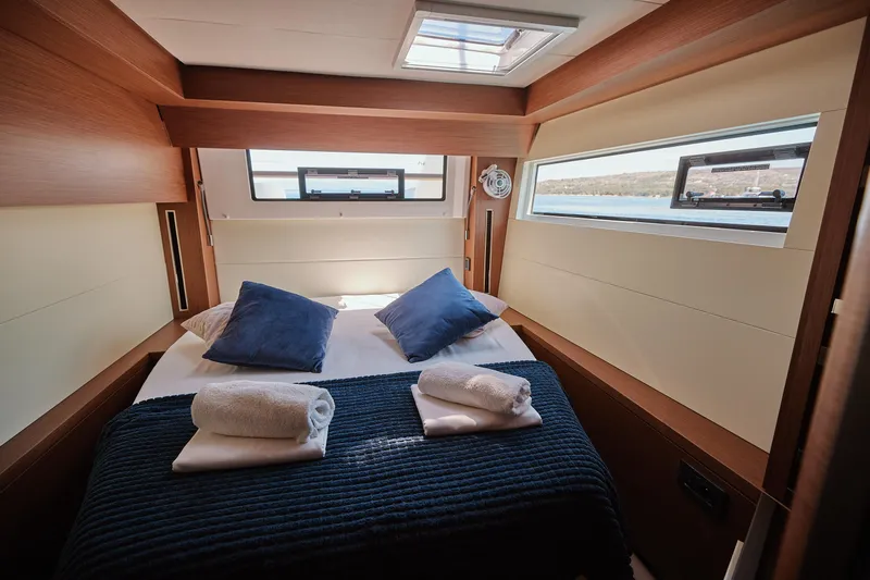 Spellbound Yacht Photos Pics Luxurious cabin interior of 2023 Lagoon 50 yacht with cozy bed and scenic windows.
