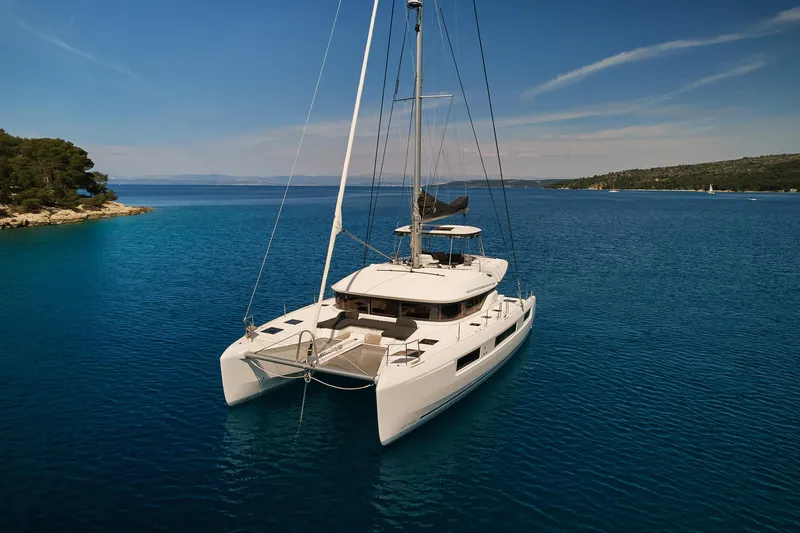 Spellbound Yacht Photos Pics 2023 Lagoon 50 catamaran sailing on clear blue waters under a sunny sky.
