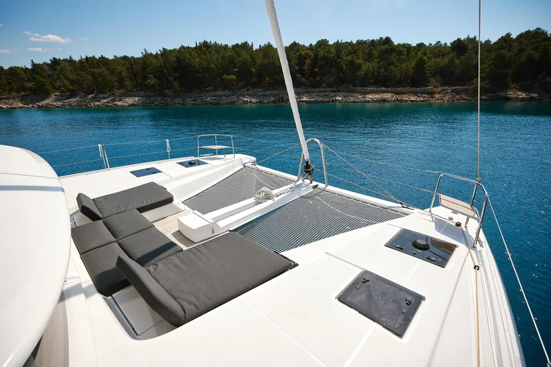 Spellbound Yacht Photos Pics Luxurious 2023 Lagoon 50 catamaran deck with sun loungers, overlooking serene blue waters.