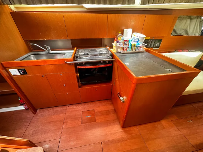 Sadalbari Yacht Photos Pics 2018 Beneteau Oceanis 41.1 yacht kitchen with wooden cabinetry, sink, stove, and storage.