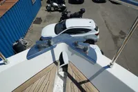Bow of Custom HARD TOP 78 yacht under construction, with cars and motorcycles in the background.
