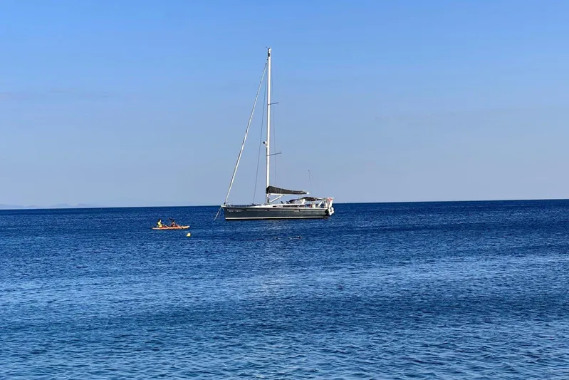Boxter Yacht Photos Pics 2013 Beneteau Sense 50 sailboat anchored on calm blue sea with a kayak nearby.