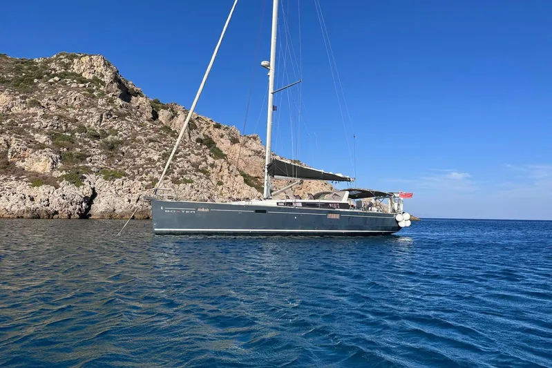 Boxter Yacht Photos Pics 2013 Beneteau Sense 50 sailboat anchored near rocky coastline under clear blue sky.