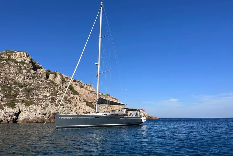 Boxter Yacht Photos Pics Sailing yacht Beneteau Sense 50, 2013 model, anchored near rocky coastline under clear blue sky.