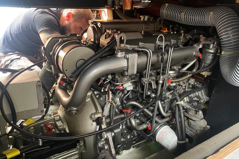 Boxter Yacht Photos Pics Mechanic working on 2013 Beneteau Sense 50 engine in a yacht's engine room.