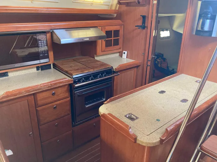 Fela Yacht Photos Pics 2009 Hunter 49 Aft Cockpit yacht kitchen with wood cabinetry and modern appliances.