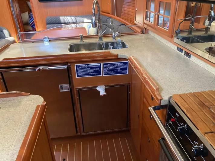 Fela Yacht Photos Pics 2009 Hunter 49 Aft Cockpit yacht kitchen with sink, stove, and wooden cabinetry.