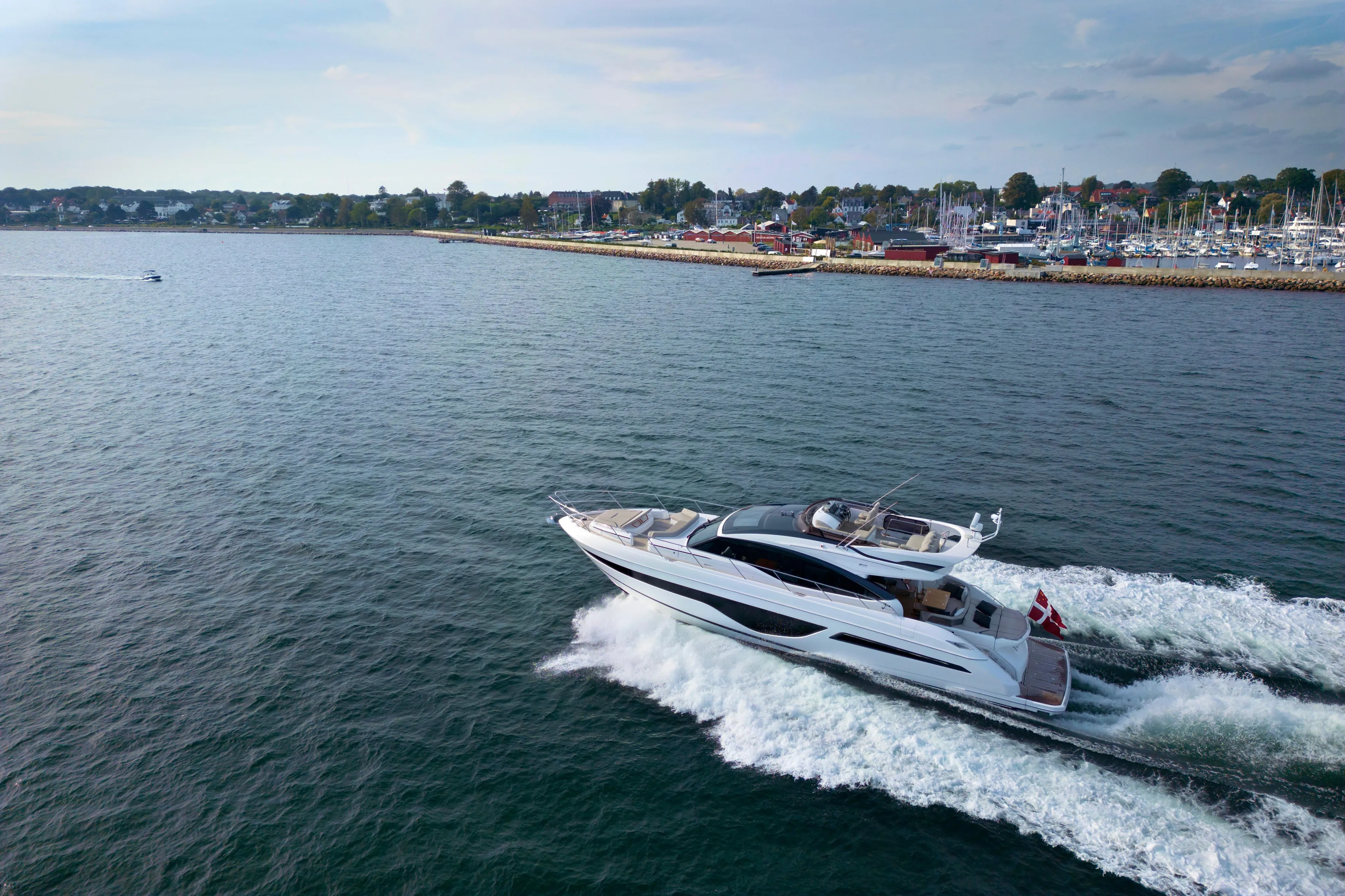  Yacht Photos Pics 2021 Princess S66 yacht cruising near a coastal town, showcasing luxury and performance.