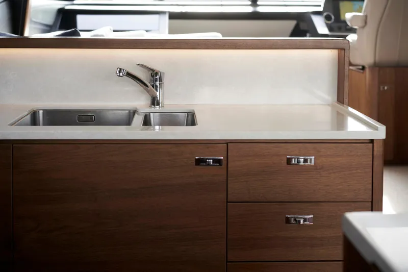  Yacht Photos Pics Luxury yacht kitchen with modern sink and wooden cabinetry, Princess S66, 2021 model.