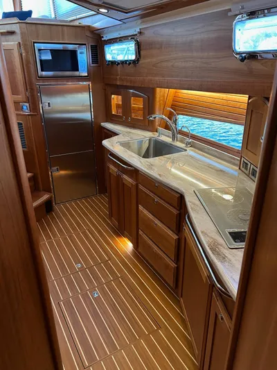 Fil The Tide Yacht Photos Pics 2021 Sabre 48 Salon Express kitchen with wood cabinetry, stainless appliances, and modern fixtures.