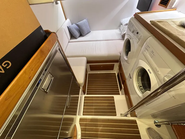 Fil The Tide Yacht Photos Pics Laundry area in 2021 Sabre 48 Salon Express yacht with washer, dryer, and seating.