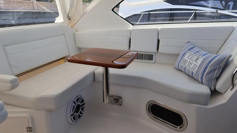  Yacht Photos Pics Luxurious interior of 2023 Pursuit OS 355 Offshore boat with cushioned seating and wooden table.
