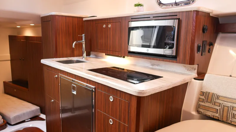  Yacht Photos Pics 2023 Pursuit OS 355 Offshore yacht kitchen with modern appliances and wood cabinetry.