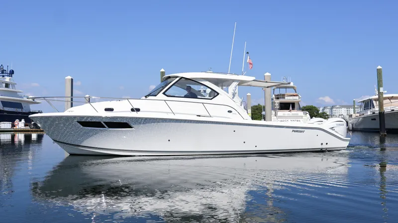  Yacht Photos Pics 2023 Pursuit OS 355 Offshore boat docked in a marina, reflecting on calm water.