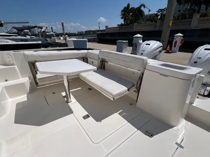  Yacht Photos Pics 2023 Pursuit OS 355 Offshore boat interior with seating and table, docked under clear skies.