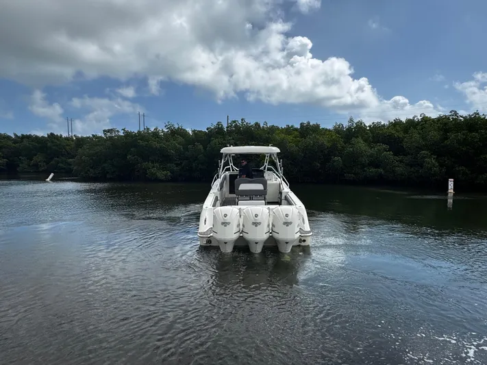  Yacht Photos Pics 2005 Hydra-Sports 3300 VX boat on calm water, surrounded by lush greenery and cloudy sky.