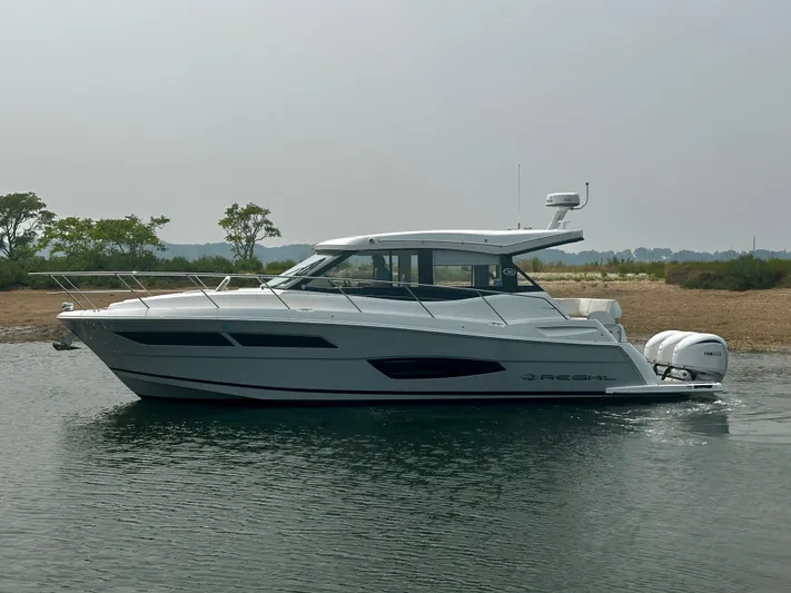  Yacht Photos Pics 2022 Regal 38 XO boat on calm water, side view with trees in the background.