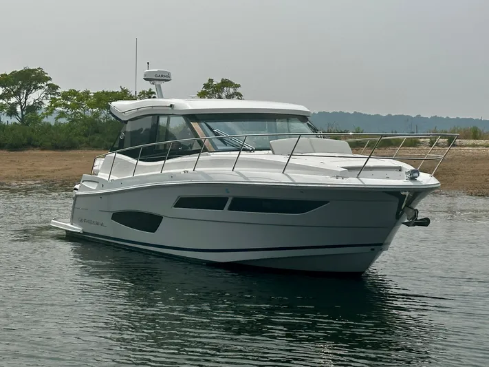  Yacht Photos Pics 2022 Regal 38 XO boat on calm water near a grassy shoreline.