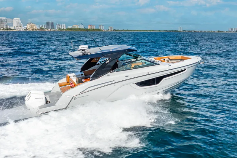 South Beach Edition -- Like New Trade In Yacht Photos Pics 2024 Cruisers Yachts 34 GLS OB speeding on ocean near city skyline.