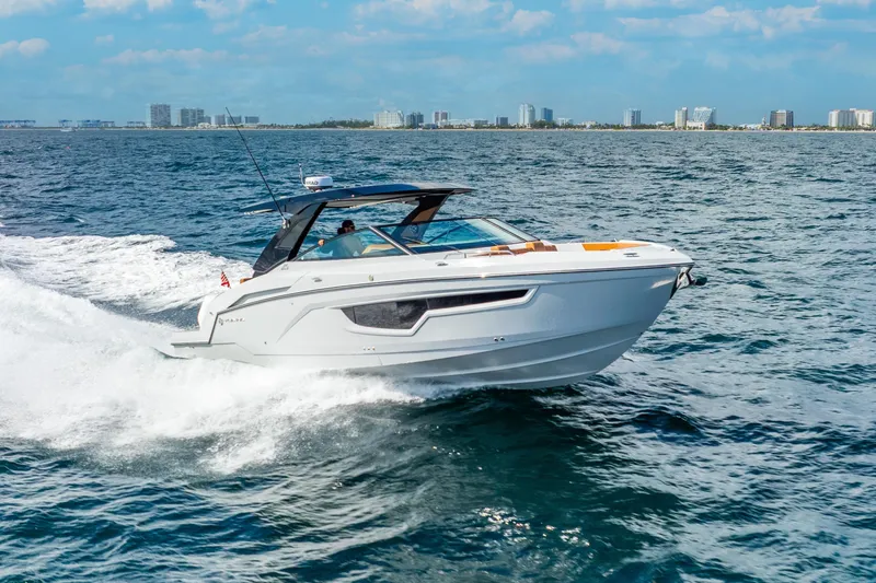 South Beach Edition -- Like New Trade In Yacht Photos Pics 2024 Cruisers Yachts 34 GLS OB cruising on open water, city skyline in background.