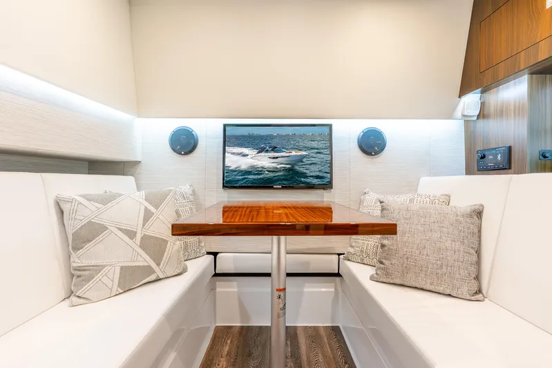 South Beach Edition -- Like New Trade In Yacht Photos Pics 2024 Cruisers Yachts 34 GLS OB interior with elegant seating, wooden table, and mounted TV.