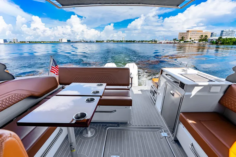 South Beach Edition -- Like New Trade In Yacht Photos Pics 2024 Cruisers Yachts 34 GLS OB interior with seating, table, and kitchenette on a sunny day.