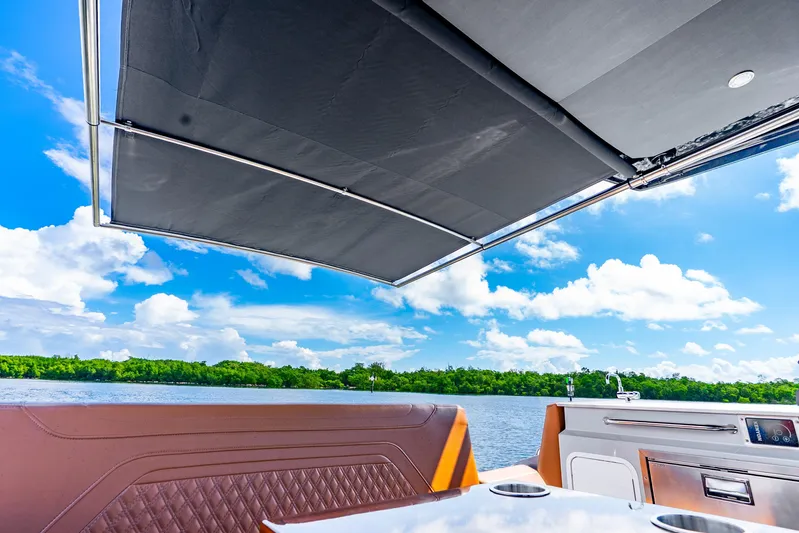 South Beach Edition -- Like New Trade In Yacht Photos Pics 2024 Cruisers Yachts 34 GLS OB interior with canopy, overlooking serene water and lush greenery.