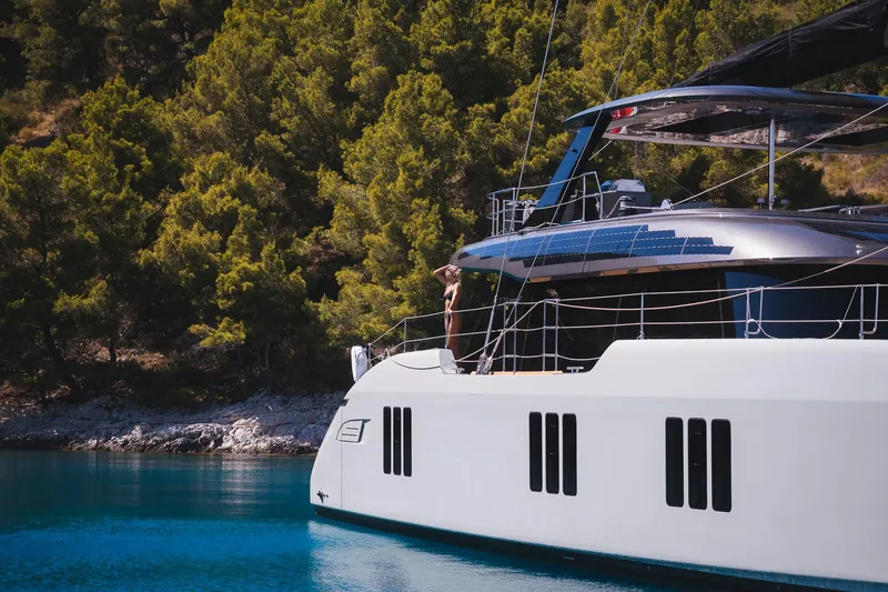 N+1 Yacht Photos Pics Luxury Sunreef 70 Eco yacht sailing near lush green coastline, 2024 model.