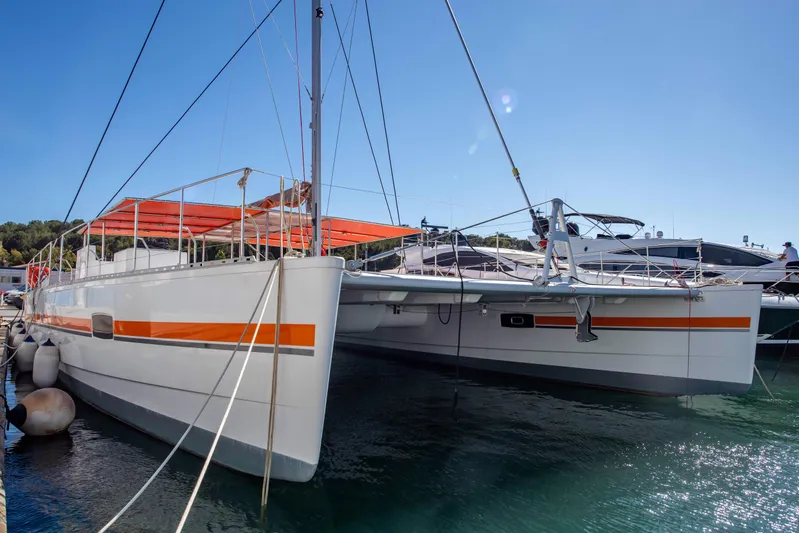 Yacht Photos Pics Custom DAYCHARTER 2026 catamaran docked, featuring sleek design and vibrant orange accents.
