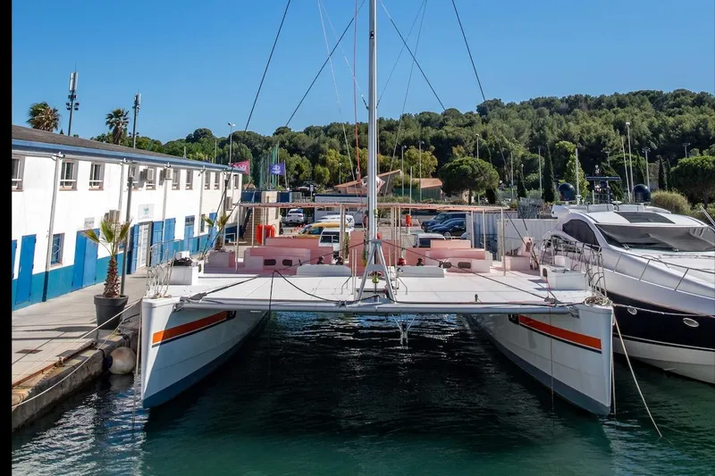  Yacht Photos Pics Modern 2026 Custom DAYCHARTER catamaran docked at marina, surrounded by yachts and lush greenery.